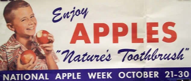 Spanduk seorang anak laki-laki memegang dua apel yang bertuliskan "Nikmati apel 'sikat gigi alam'"